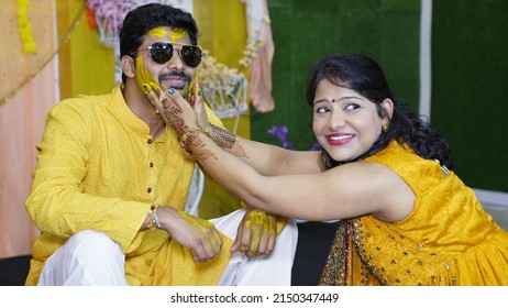 Sister applying haldi on face of his brother during haldi ceremony