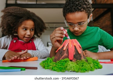 Sister And Brother Having Fun Making DIY Volcano Model From Kids Play Clay For School Project. Home Education Concept.