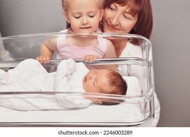 The sister and grandmother looks at a newborn baby in the hospital ward