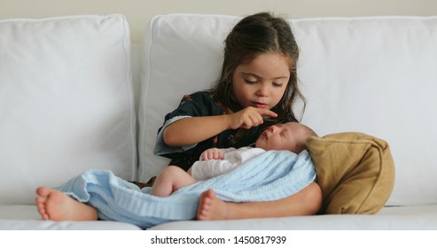 Sister holding newborn baby infant kissing showing love and affection