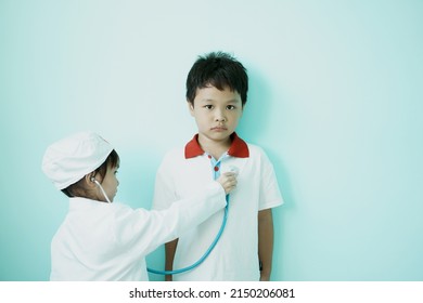 ฺBrother and sister are playing doctor and hospital using stethoscope toy and medical uniform at home. Soft focus.