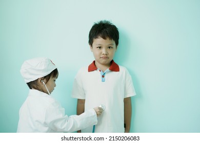 ฺBrother and sister are playing doctor and hospital using stethoscope toy and medical uniform at home. Soft focus.