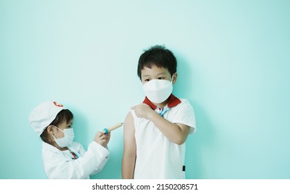 ฺBrother and sister are playing doctor and hospital using toy wooden syringe  and medical uniform at home. Soft focus.