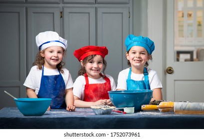 Sisters In Chef Hats And Aprons Making Blueberry Pie In The Kitchen