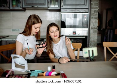 Sisters do makeup at home in kitchen. first teen makeup.Two beauty blogge cute girls presenting beauty cosmetic products . broadcasting live video to social network. blogger concept.