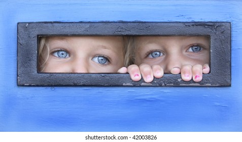 Sisters Hiding Behind A Door Peeping Thru A Letter Box