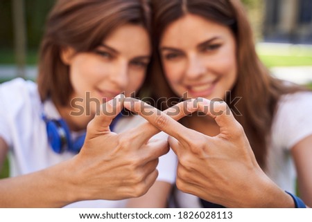 Sisters making infinity symbol with their hands. Focus on the hands, blurred girls on the background. Concept of relationships, sisterly love