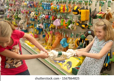 Sisters Playing Tug Of War With Dog Toy