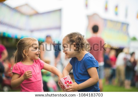 Sisters sharing popcorn at fair