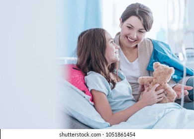Sisters smiling and lying in bed in the hospital together. Family support during illness concept - Shutterstock ID 1051861454