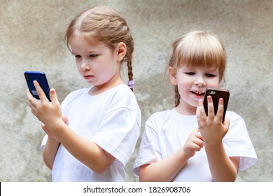 Sisters, young children using modern smartphones, two girls together holding and using their mobile phones, playing around. Tech savvy generation, kids and modern technology concept, outdoors shot - Shutterstock ID 1826908706