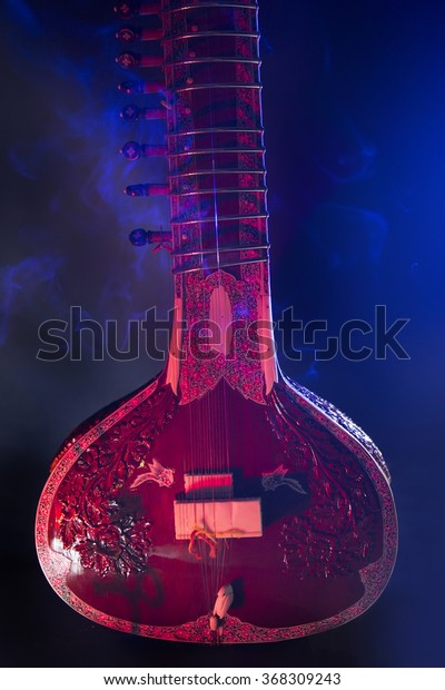 Sitar, a String Traditional
Indian Musical Instrument, close-up, blue lens effect. dark
background with incense smoke. Evening of ethnic oriental music.
Indian Raga