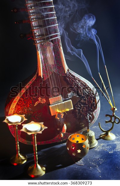 Sitar, a String Traditional\
Indian Musical Instrument, close-up, blue lens effect. dark\
background with incense smoke. Evening of ethnic oriental music.\
Indian Raga