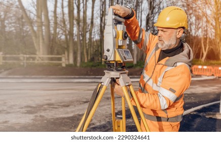 Site engineer operating his touch screen controller instrument during roadworks. Builder using touch screen controller to control total positioning station tacheometer on construction site   