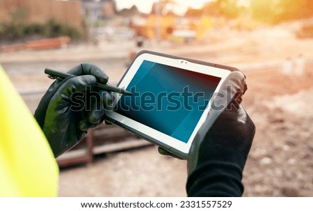 Site engineer surveyor using rugged tablet controller computer to operate EDM total station for setting out and surveying close-up