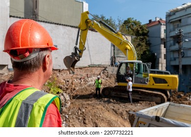 Site manager   standing at the construction site of a private property, supervising, inspecting or overseeing the work progressProcess of demolition of old building dismantling. 