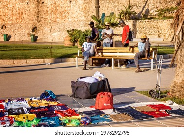 Sitges, Spain, June 11, 2018.
Illegal Black Immigrants Selling Shirts And Shoes At The Marine Drive In Sitges, Spain. Sitges, Close To Barcelona, Is Also Known For Its Gay Community