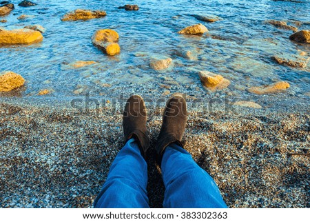 Siting on the beach with awesome landscape of bright sunset at the seashore on the background. Natural colorful view