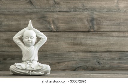 Sitting buddha. White monk statue on wooden background. Meditation. Relaxing. Retro style toned picture