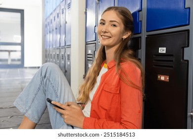 Sitting by lockers, teenage girl using smartphone and smiling in school hallway. Teen, technology, education, communication, social media, lifestyle - Powered by Shutterstock