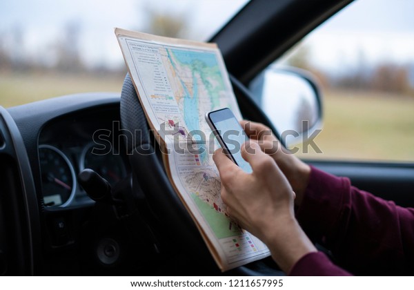 sitting in the car driver hands holding\
the map and searching the way out, lost in forest\
