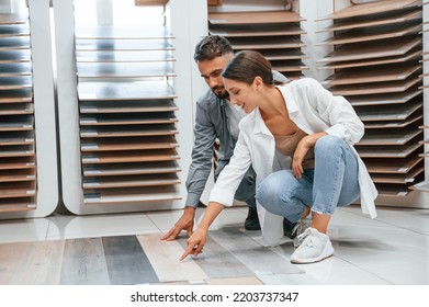 Sitting and choosing parquet. Woman and man is in the store of goods for the home.