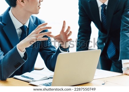 Sitting at a desk and talking about business with colleagues and bosses in front of a laptop, a man without a face in a suit