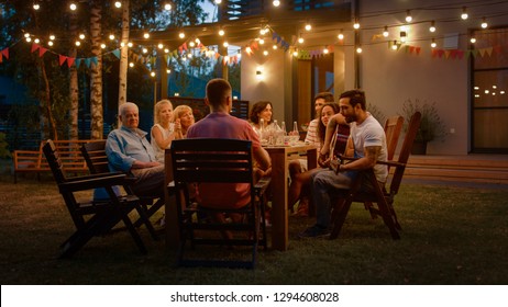 Sitting at the Dinner Table Handsome Young Man Plays the Guitar For a Friends. Family and Friends Listening to Music at the Summer Evening Garden Party Celebration. - Shutterstock ID 1294608028