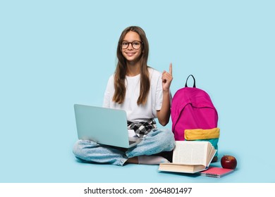 Sitting full-length teenager schoolgirl with laptop computer showing pointing on copy space having idea, surfing webpages on Internet,social media,e-learning remotely isolated in blue background
