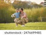 Sitting, holding soccer ball. Happy father with son are having fun on the field at summertime.