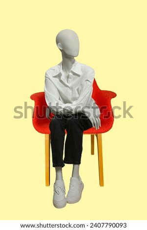 Sitting image of a female display mannequin wearing white shirt and black trousers isolated on yellow background