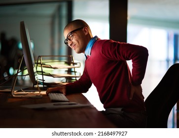 Sitting For Too Long Can Have Adverse Effects. Shot Of A Young Man Holding His Back In Pain While Working Late In The Office.