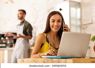 Sitting near laptop. Dark-haired successful female entrepreneur sitting near laptop while ordering foods - Shutterstock ID 1495825955