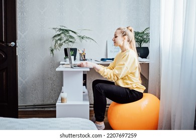 Sitting On Gym Ball At Work. Use Exercise Ball Like Chair At Workplace. Freelancer Woman Sitting On Orange Fitness Ball Using Laptop In Home Office