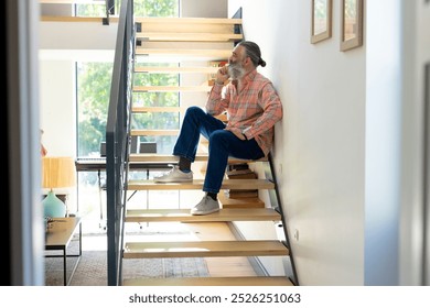 Sitting on stairs, senior man drinking coffee and looking out window at home. relaxation, morning, unaltered - Powered by Shutterstock