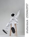 Sitting on a wooden chair astronauts pointing up with finger, white background