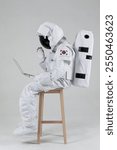 Sitting on a wooden chair with a laptop and a video call, the astronauts in the hands greeting, white background