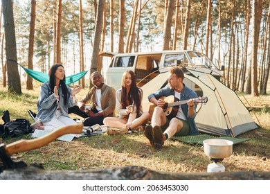 Sitting and resting. Group of young people is traveling together in the forest at daytime.