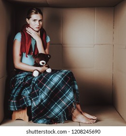 Sitting Sick Young Woman In Scarf With Blanket. Girl With Toy Bear. Life In Little Cardboard Box. Uncomfortable Life. Personal Spase Concepts. Girl In Red Scarf. Healthcare Concept.