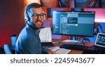 Sitting and smiling. Professional programmer is working indoors. Neon lighting.