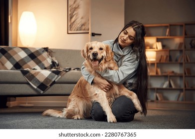 Sitting and smiling. Woman is with golden retriever dog at home. - Powered by Shutterstock