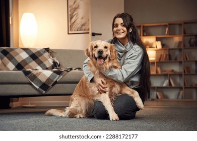 Sitting and smiling. Woman is with golden retriever dog at home. - Powered by Shutterstock