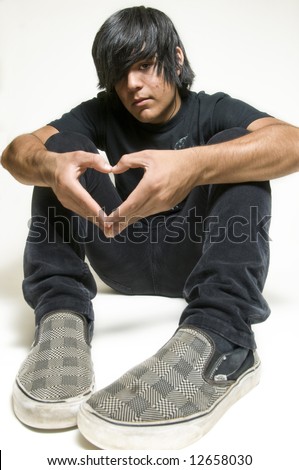 Sitting teenage boy making heart symbol with hands