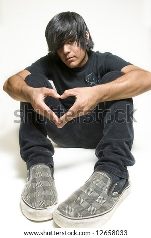 Sitting teenage boy making heart symbol with hands