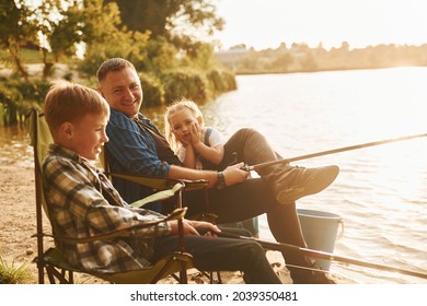 Sitting together. Father with son and daughter on fishing outdoors at summertime. - Powered by Shutterstock