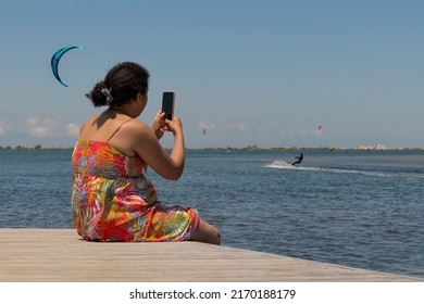 Sitting Woman On A Pontoon Bridge With A Kite Surfer