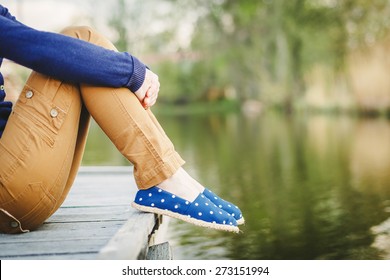 Sitting Woman's feet in a sneakers near the lake - Powered by Shutterstock