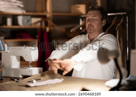 Sitting at workplace, man tailor does limbering
