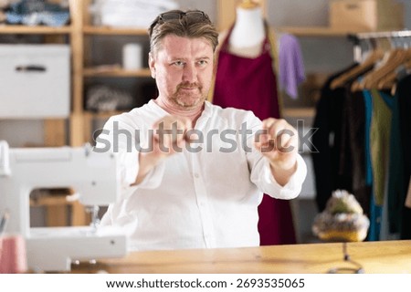 Sitting at workplace, man tailor does limbering