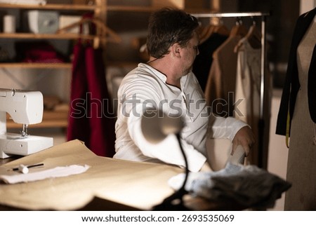 Sitting at workplace, man tailor does limbering